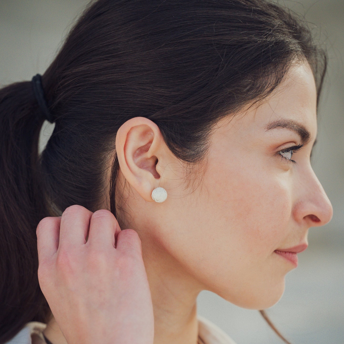 Modelo de perfil mostrando pendientes en plata 950 con diseño de filigrana y el nudo tradicional de Santa Fe de Antioquia, resaltando elegancia y tradición colombiana en el mercado estadounidense
