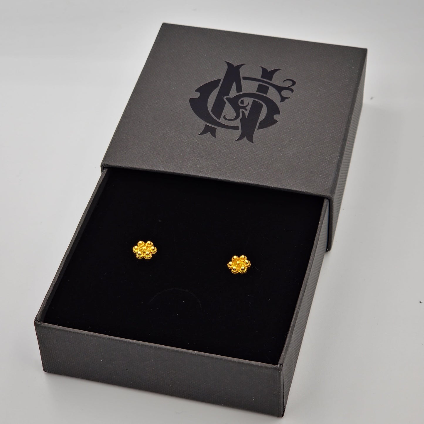 Aretes artesanales de flor en oro con filigrana, elaborados a mano con un diseño delicado y sofisticado, reflejando la tradición y excelenci