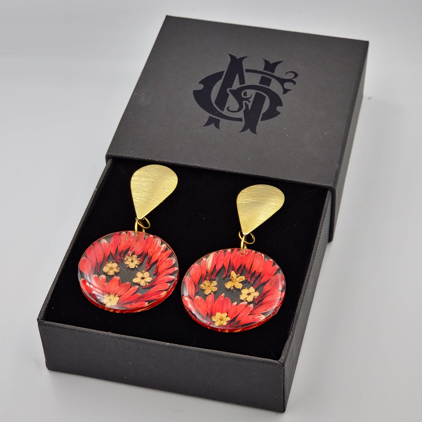 Aretes artesanales de flores naturales encapsuladas en resina con detalles en oro laminado, hechos a mano con un diseño elegante y sofisticado, ideales para un estilo fresco y atemporal.