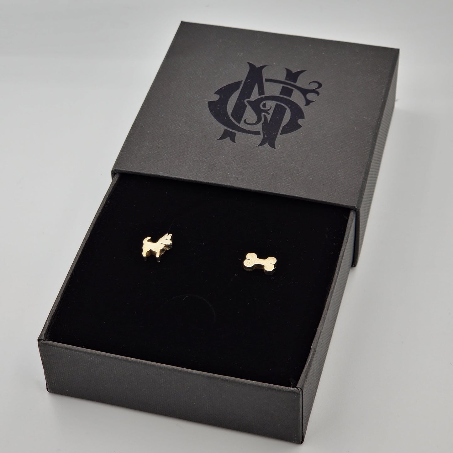 Aretes artesanales de huesito y perrito en plata, elaborados a mano con un diseño elegante y divertido, ideales para amantes de los perros y la joyeria.