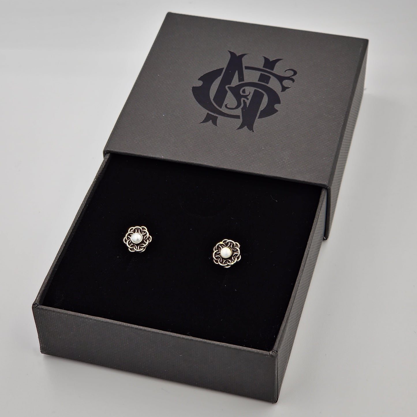 Aretes artesanales de flor en plata quemada, elaborados a mano con un diseño texturizado y sofisticado, resaltando la belleza de la orfebrería tradicional.