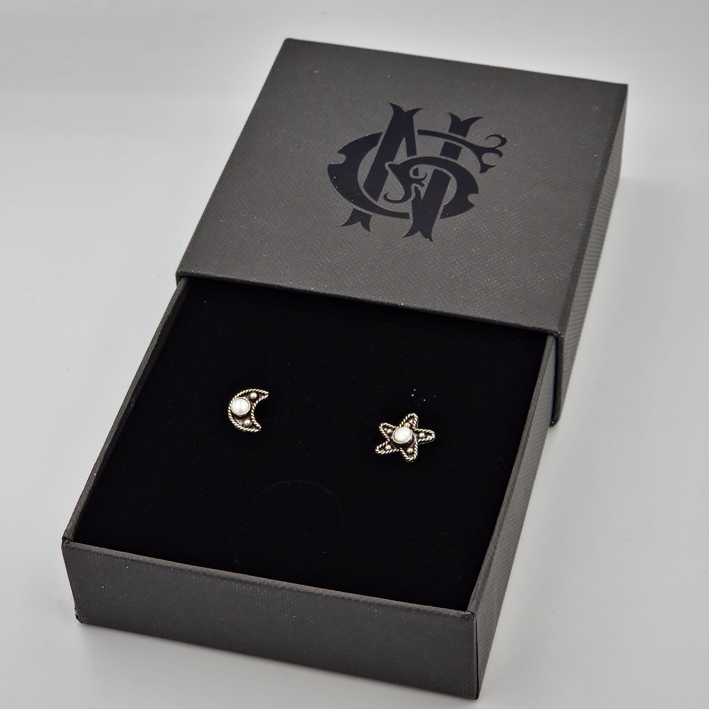 Aretes artesanales de luna y estrella en plata quemada, elaborados a mano con un diseño elegante y texturizado, reflejando tradición y sofisticación en cada detalle.