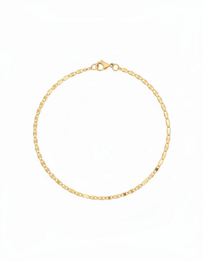 Woman wearing 18k gold filled flat ladder anklet, 25cm diamond-cut gold chain, waterproof luxury jewelry, hypoallergenic, beach-ready ankle bracelet.