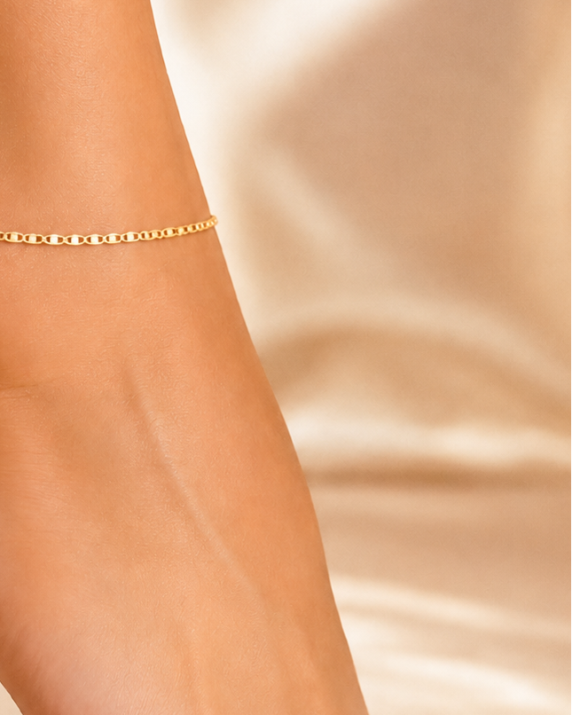 Woman wearing 18k gold filled flat ladder anklet, 25cm diamond-cut gold chain, waterproof luxury jewelry, hypoallergenic, beach-ready ankle bracelet