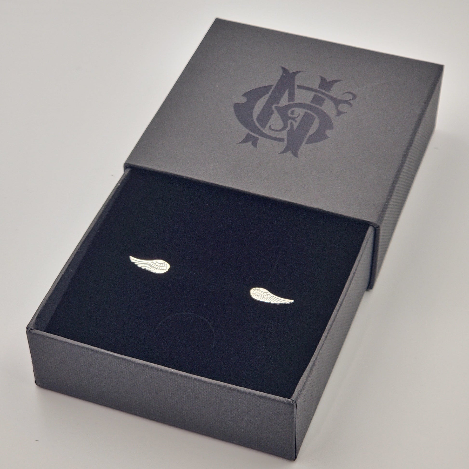 Topos artesanales en plata 925 en forma de alitas de 14 x 5 mm, hechos en Santa Fe de Antioquia y presentados en caja de lujo negra