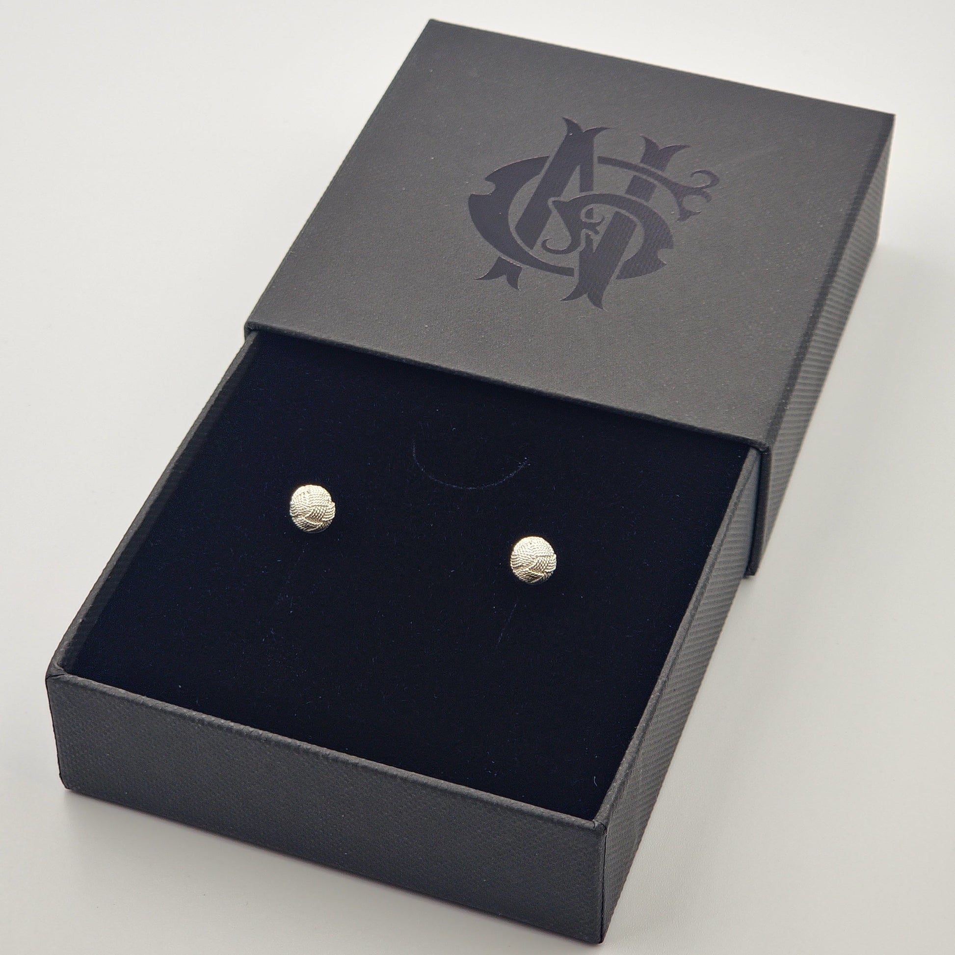 Topos de filigrana en plata 925 con forma de flor, inspirados en tejidos típicos de Santa Fe de Antioquia, presentados en caja elegante negra